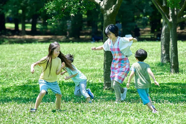 Eine Frau Schürze Mit Spielenden Kindern Bei Einer Verfolgungsjagd Park — Stockfoto