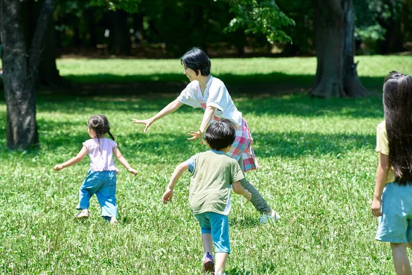 Una Donna Grembiule Con Bambini Che Giocano Caccia Nel Parco — Foto Stock