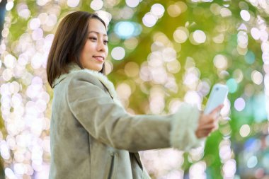 Geceleri sokak ağaçlarının aydınlatma ışıklarının tadını çıkaran bir kadın.