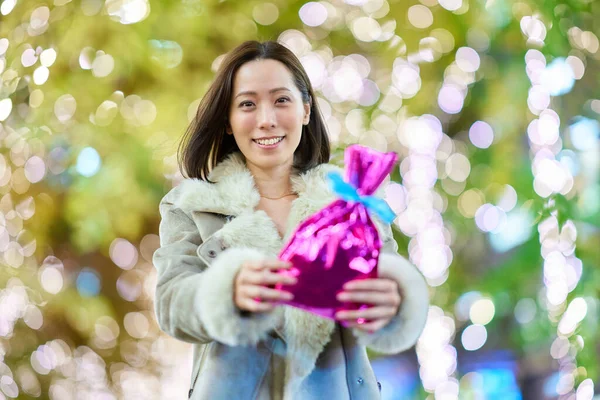 一个女人 晚上在户外拿着一个彩色包裹的礼物 — 图库照片