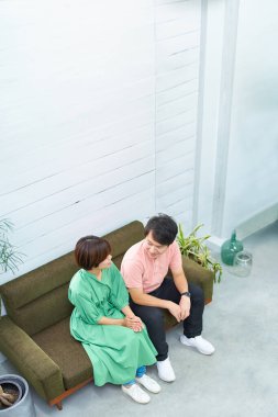 Genç bir adam ve kadın kanepede oturuyor ve konuşuyorlar.