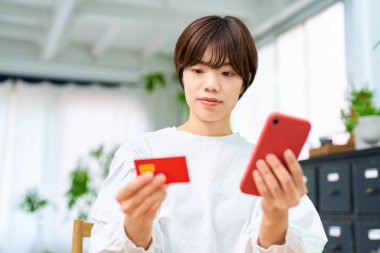 Elinde kart tutan ve akıllı telefon kullanan bir kadın.