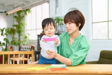 Ebeveyn ve çocuk evde origami oynuyorlar