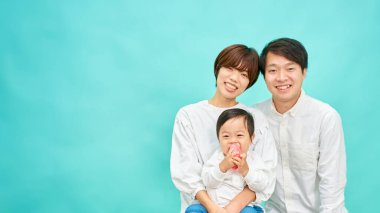 Mavi arka planda üç kişilik bir ailenin portresi.