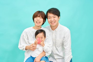 Mavi arka planda üç kişilik bir ailenin portresi.