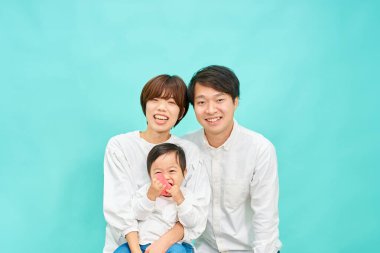 Mavi arka planda üç kişilik bir ailenin portresi.