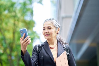 Dışarıda akıllı telefon tutan kıdemli bir kadın.