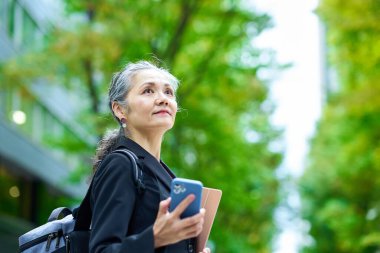 Dışarıda akıllı telefon tutan kıdemli bir kadın.