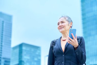 Dışarıda akıllı telefon tutan kıdemli bir kadın.