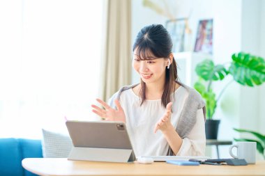 Odadaki tabletle internet üzerinden iletişim kuran genç bir kadın.