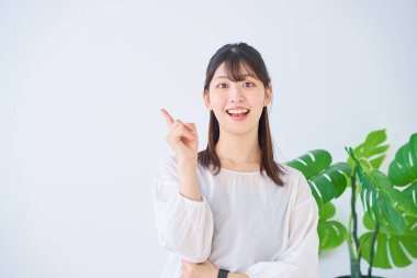 İşaret parmağıyla içeride poz veren genç bir kadın.