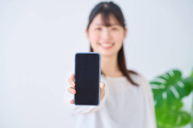 İçeride akıllı telefon ekranı gösteren genç bir kadın.