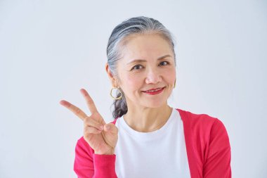 Kıdemli kadın odada barış işareti yapıyor.                   