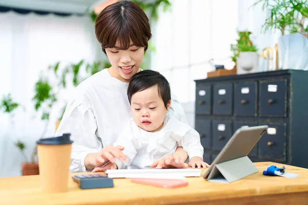 Woman Holding Baby Operating Computer Indoors — Stock Photo, Image