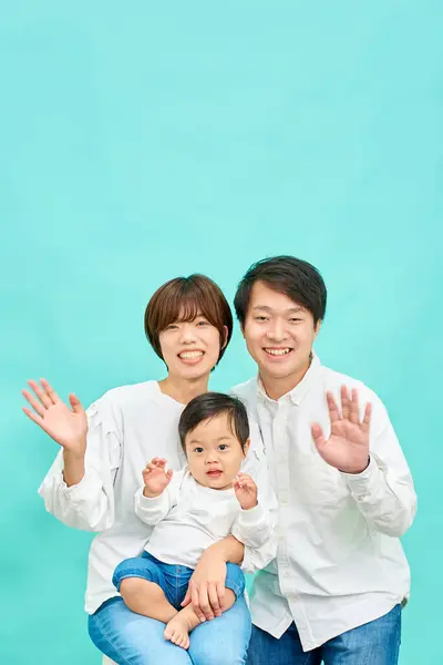 Una Familia Sonriente Agitando Sus Manos Frente Fondo Azul — Foto de Stock