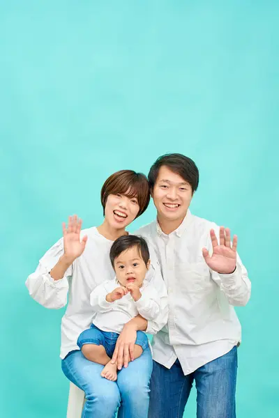 青い背景の前に手を振る笑顔の家族 — ストック写真