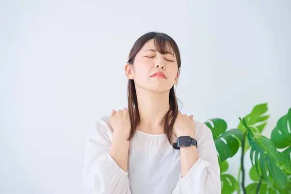 young woman suffering from stiff shoulders indoors