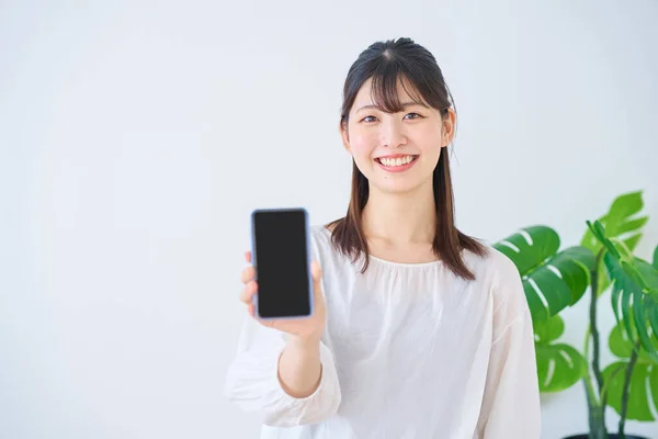 stock image Young woman showing smartphone screen indoors