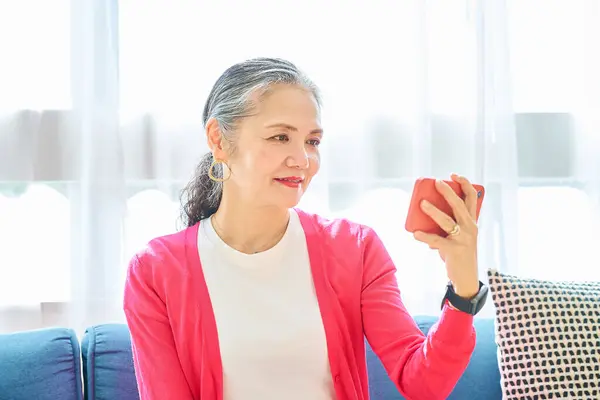Starsza Kobieta Patrzy Ekran Smartfona Pomieszczeniach — Zdjęcie stockowe