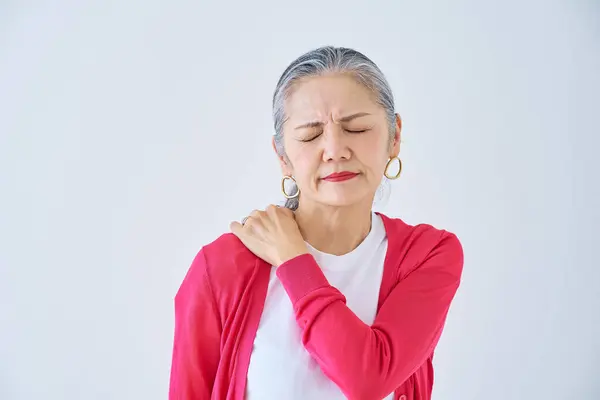 Senior woman suffering from stiff shoulders indoors