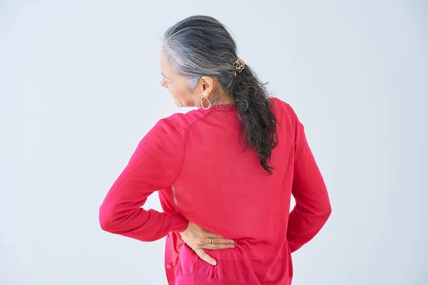 一名老年妇女在室内背痛的后视镜 — 图库照片