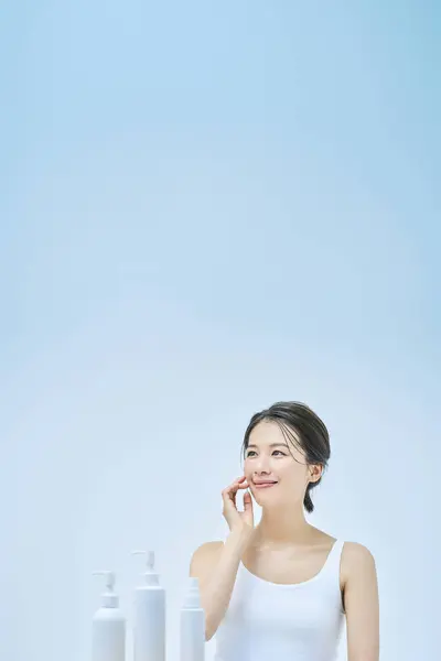 woman doing skin care and pale blue background