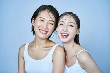 İki kadın kolsuz elbiseler içinde dizilmiş.