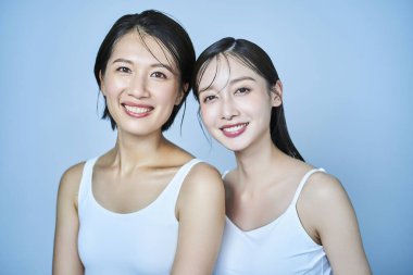 İki kadın kolsuz elbiseler içinde dizilmiş.