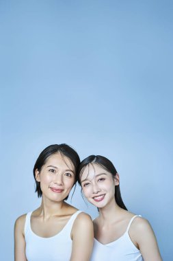 İki kadın kolsuz elbiseler içinde dizilmiş.