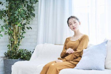 Gülümseyen genç kadın, odasında rahat rahat dinleniyor.