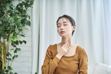 Gecelik giyen genç bir kadın odasında boğazında rahatsız hissediyor.