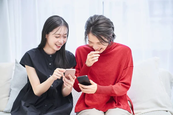 部屋でスマートフォンを見ている2人の女性 — ストック写真