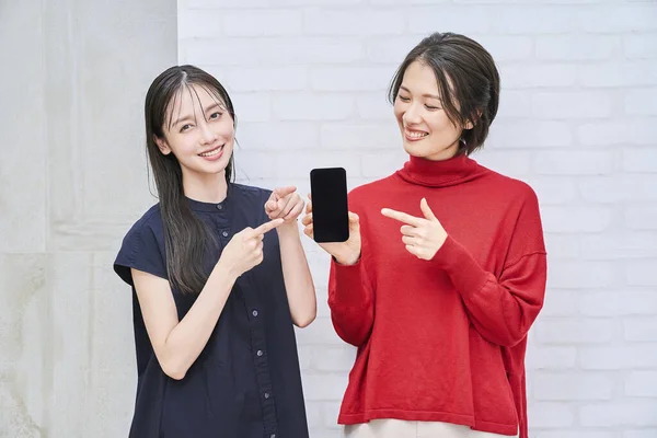 部屋でスマートフォンを見ている2人の女性 — ストック写真