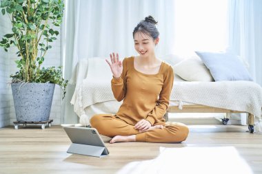 Loungewear giyen genç bir kadın tablet ekrana bakıyor.