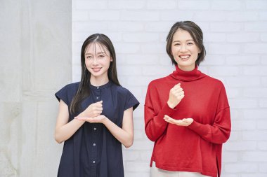 İki kadın gülümsüyor ve içeride inandırıcı bir şekilde poz veriyor.