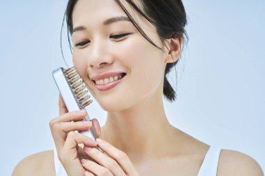 Güzellik aletlerini kullanarak kendine masaj yapan bir kadın.