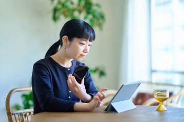 Odadaki bilgisayarla akıllı telefonu karşılaştıran genç bir kadın.