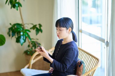 Odada akıllı telefon kullanan genç bir kadın.