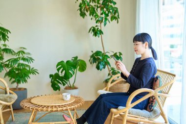 Odada akıllı telefon kullanan genç bir kadın.