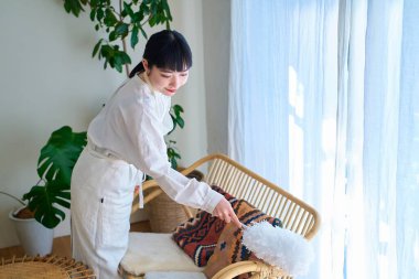 Odanın her köşesinden toz temizleyen genç bir kadın.