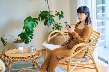 Odada akıllı telefon kullanan genç bir kadın.