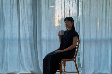 Gün batımında pencerenin kenarında dinlenen genç bir kadın.