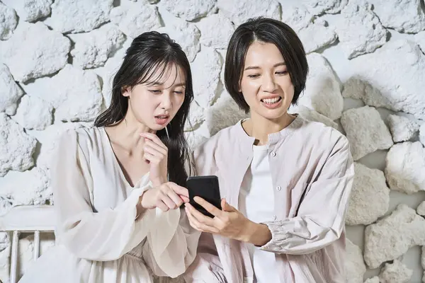 Zwei Frauen Blicken Mit Misstrauischen Mienen Auf Ihre Smartphone Bildschirme — Stockfoto