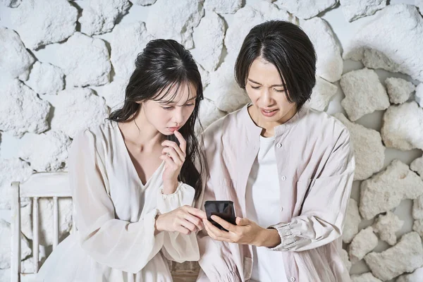 Zwei Frauen Blicken Mit Misstrauischen Mienen Auf Ihre Smartphone Bildschirme — Stockfoto