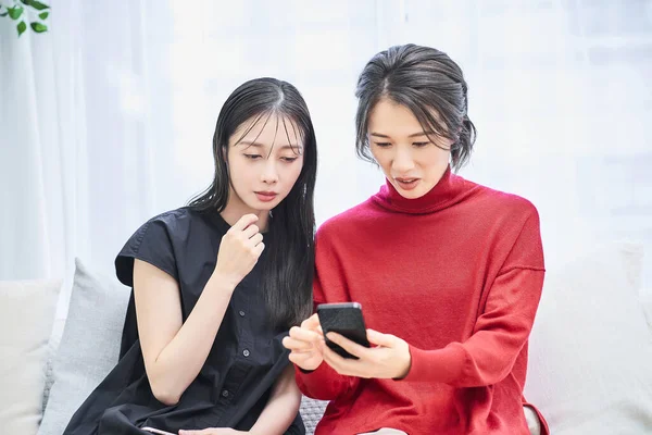 Две Женщины Смотрят Свои Смартфоны Тревожными Выражениями — стоковое фото