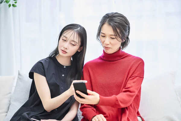 Two women looking at their smartphones with anxious expressions