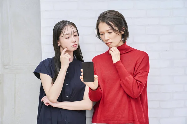 Två Kvinnor Tittar Sina Smartphones Med Oroliga Uttryck — Stockfoto