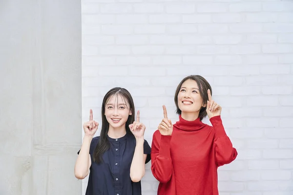 2人の日本人女性が屋内を上向きに指差す — ストック写真