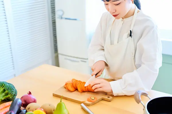 キッチンでナイフで食材を切る若い女性 — ストック写真