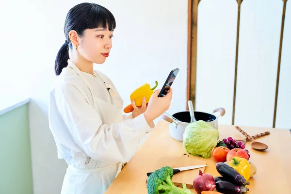 Junge Frau Holt Gemüse Und Smartphone Der Küche — Stockfoto